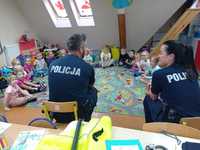 policjanci prowadzą pogadankę z dziećmi, dzieci siedzą przed nimi na dywanie w kółku oni na krzesłach