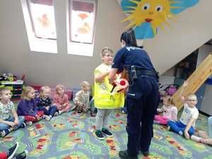 policjantka pomaga dziecku ubrać kamizelke