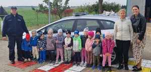 policjanci wraz z dziećmi pozują do zdjęcia w przy radiowozie