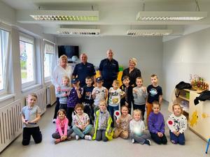 policjanci wraz z dziećmi pozują do zdjęcia w sali przedszkolnej