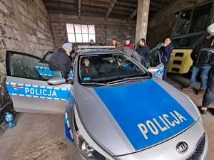 policjanci przy radiowozie ćwicza wyciąganie z samochodu - w garażu stoi radiowóz, w środku siedzą osoby