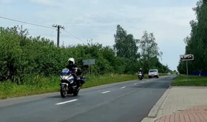 policjanci na motocyklach wjeżdżają drogą do obszaru zabudowanego