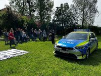 Radiowóz policji stoi na trawniku, wokół dzieci z opiekunami